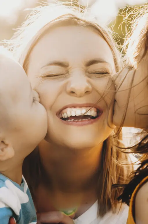 Picture of two children kissing their mom on the cheeks.